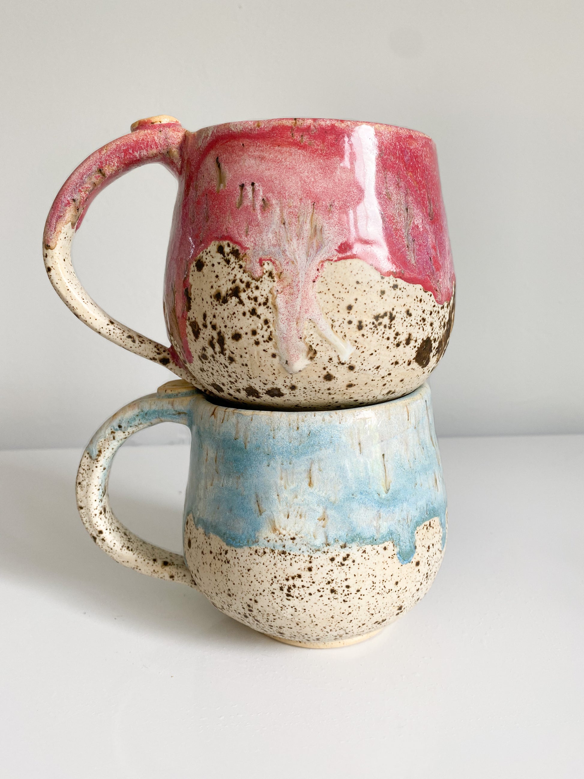 back view of moon mugs one glazed in raspberry and the other in blue